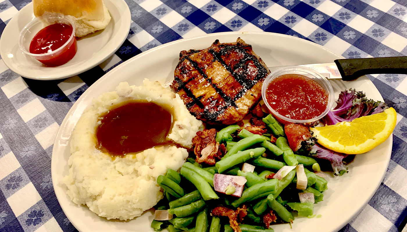 A plate of mashed potatoes, gravy, green beans and grilled chicken.
