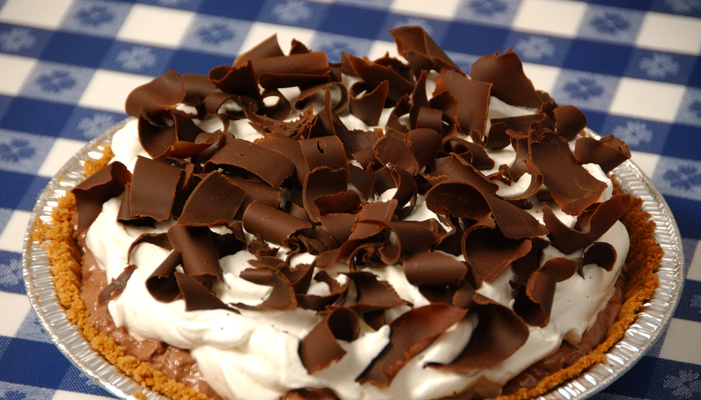 A chocolate cream pie topped with whipped cream and chocolate shavings.