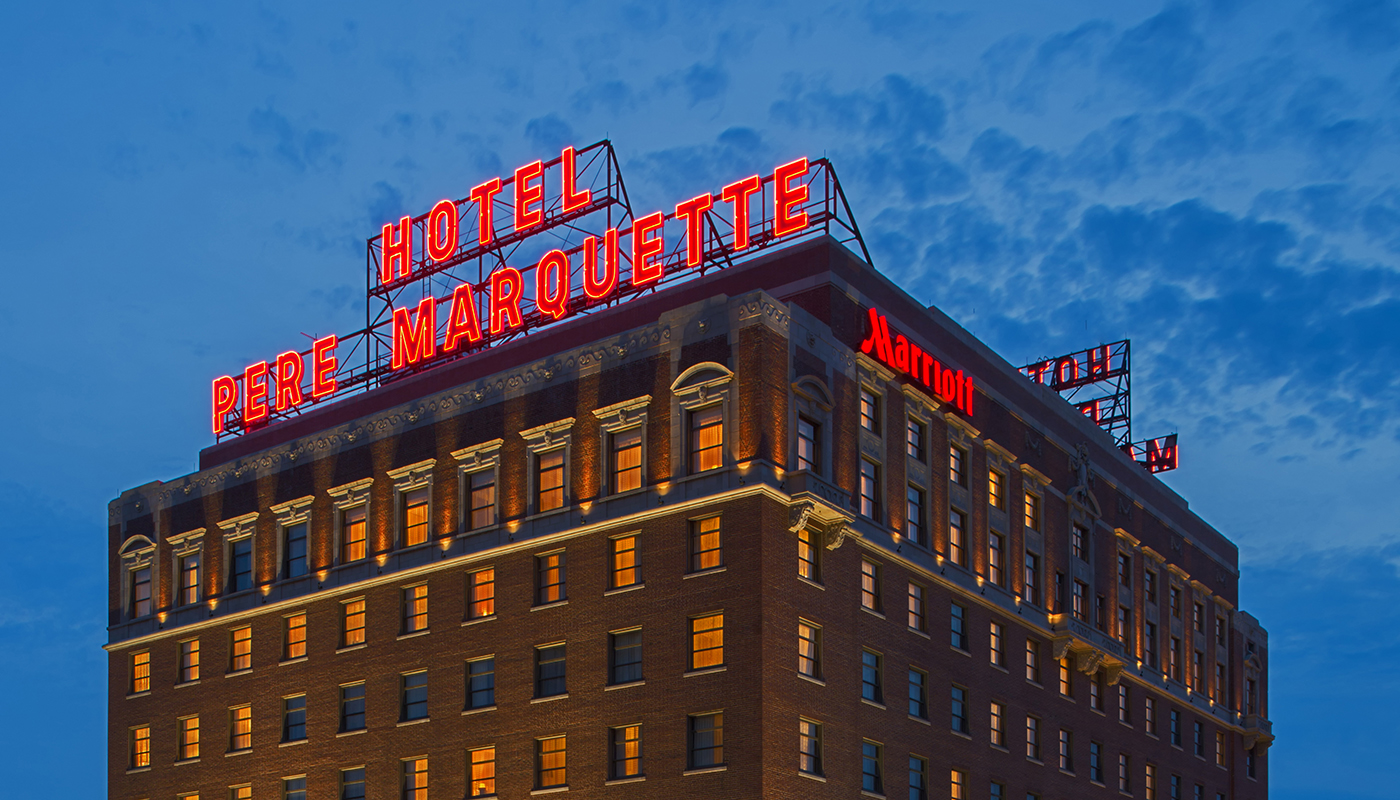 Roof top of hotel with a red neon sign reading, “HOTEL PERE MARQUETTE.”