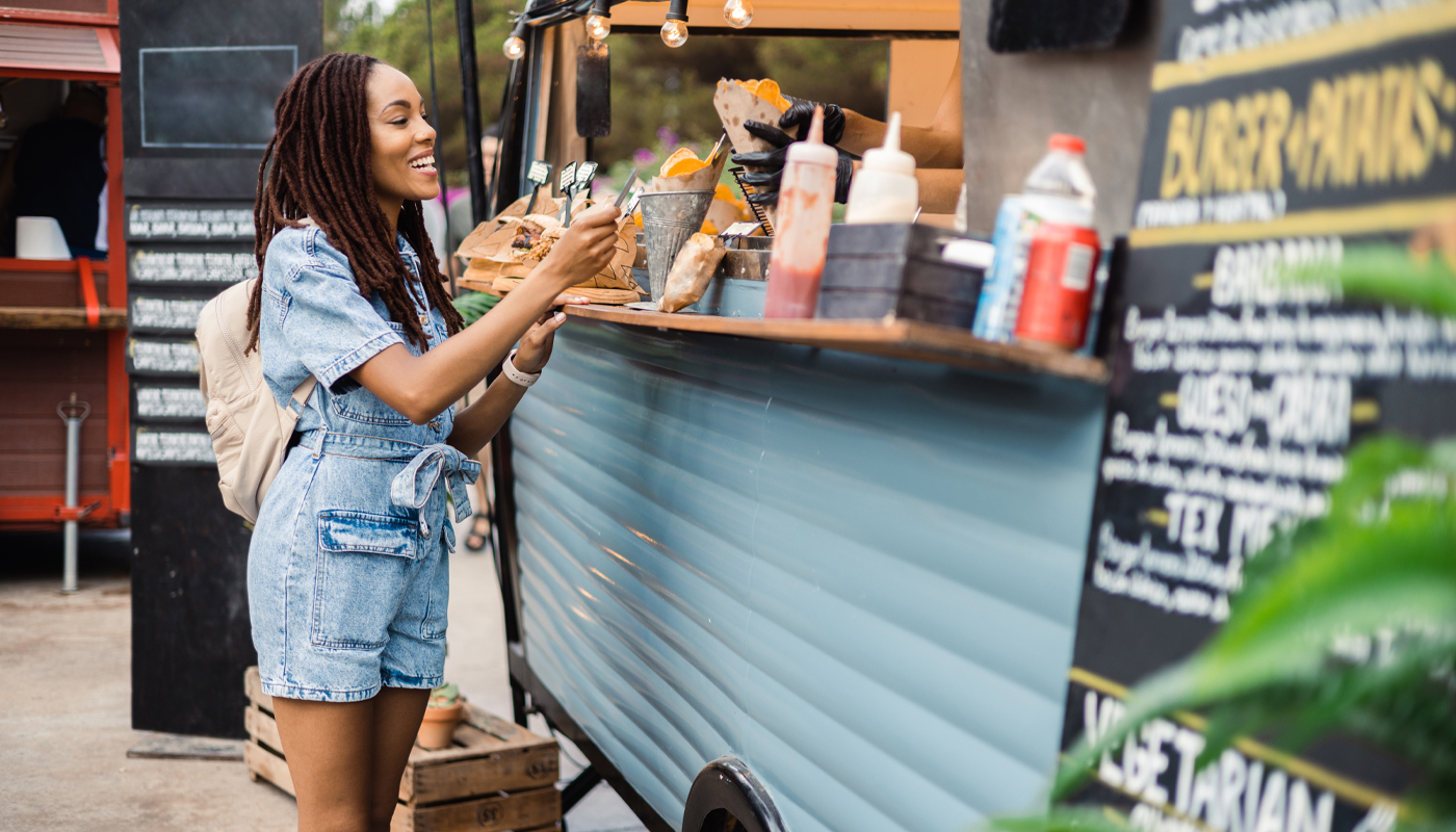 A smiling woman receives her order at a food truck.