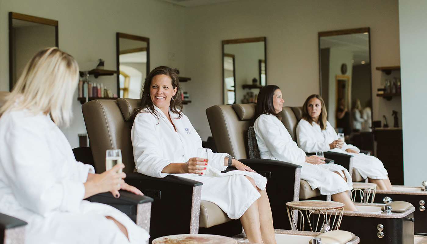 A group of women enjoy pedicure treatments together while drinking champagne
