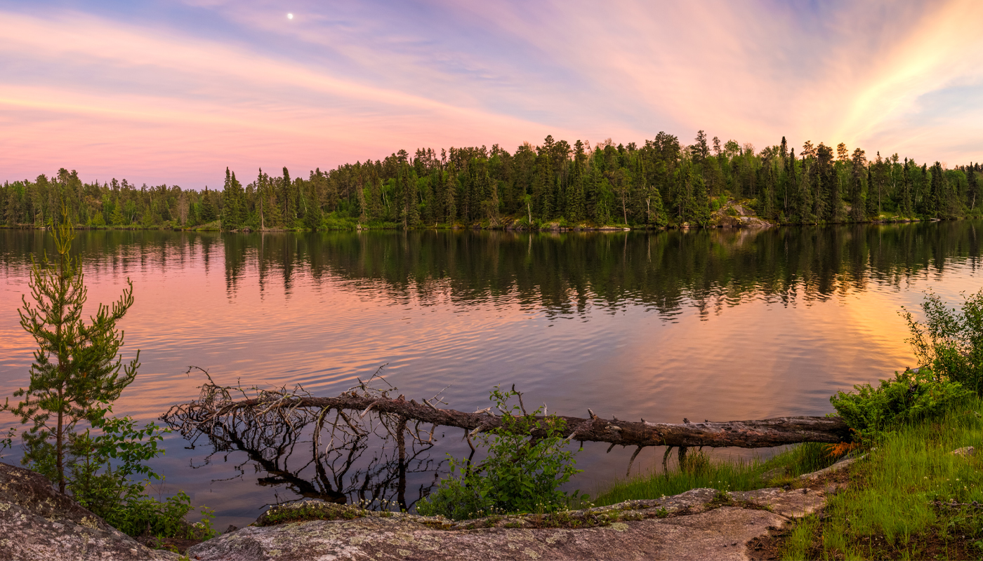 A lake surrounded by trees at sunset.