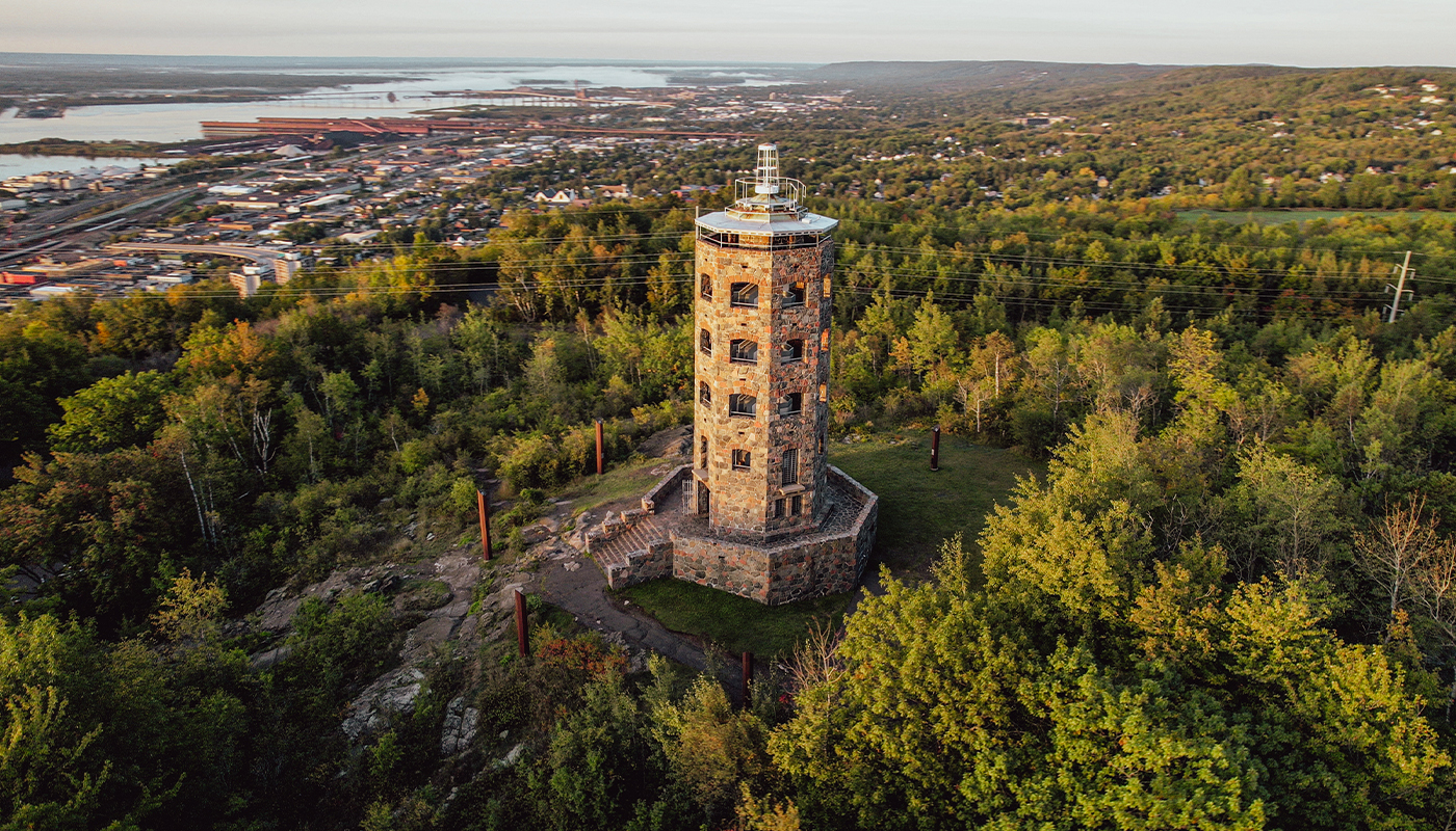 A five-story stone tower stands above the trees and the city beyond them. 