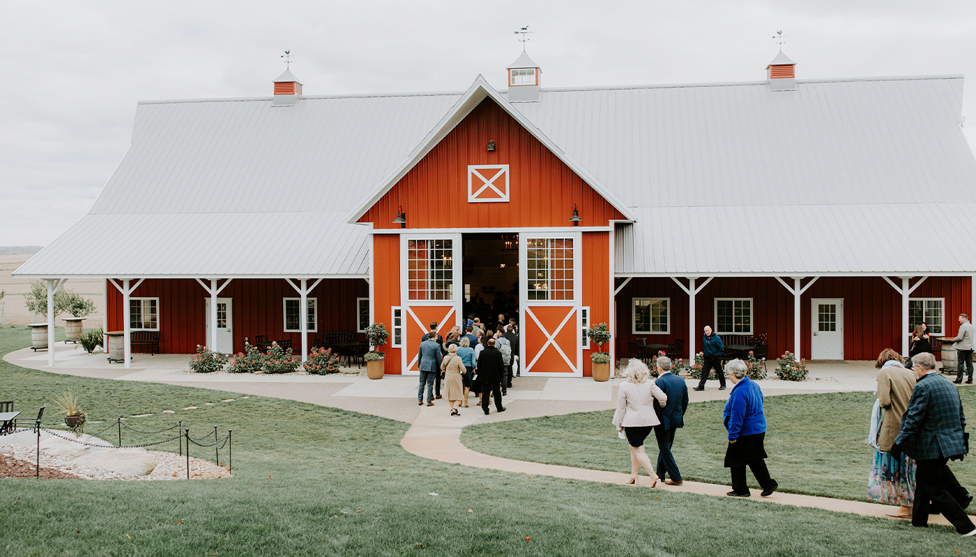 Patrons walk into a large red barn. 