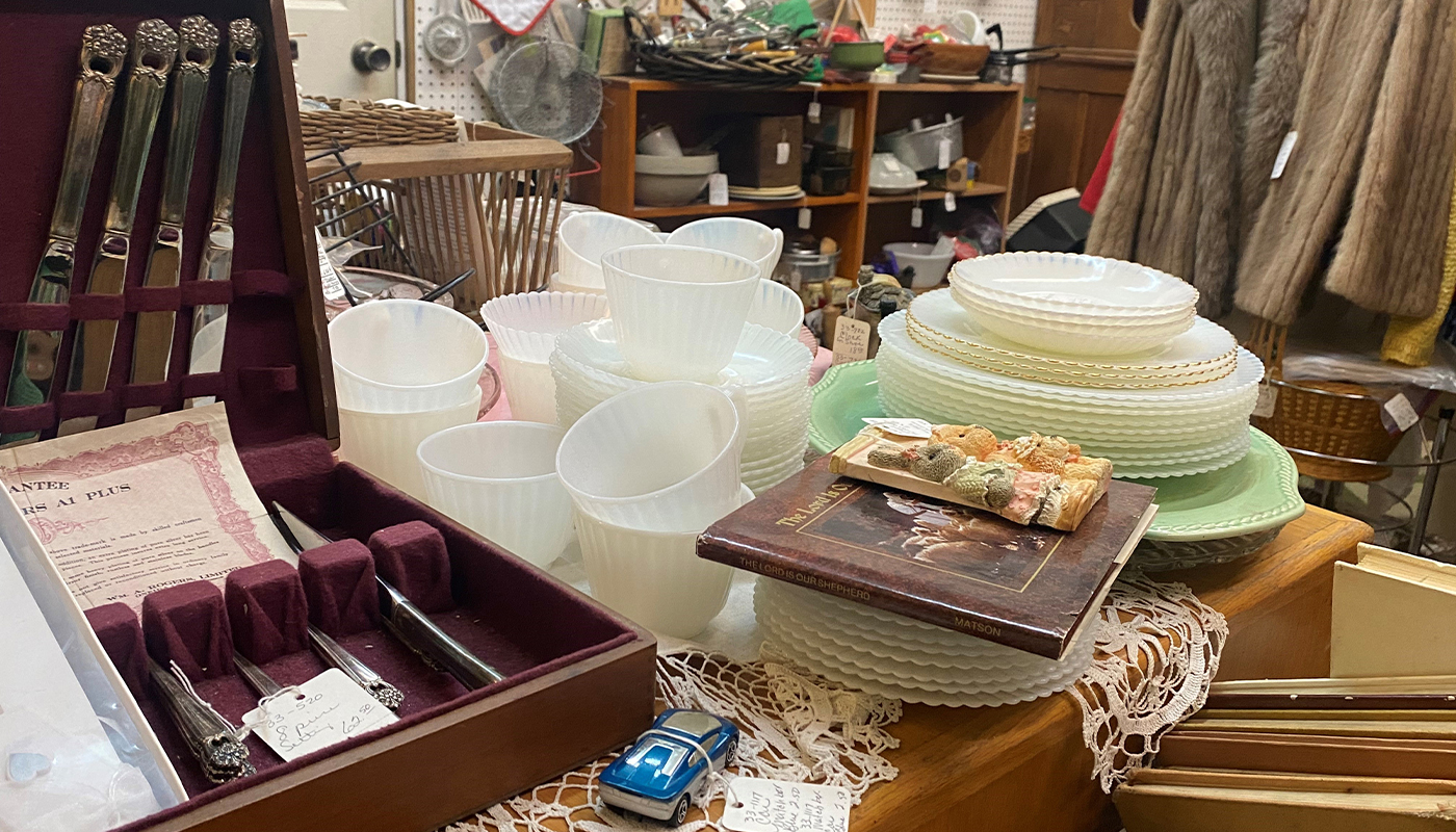 Antique china displayed on a table next to a box of silverware.