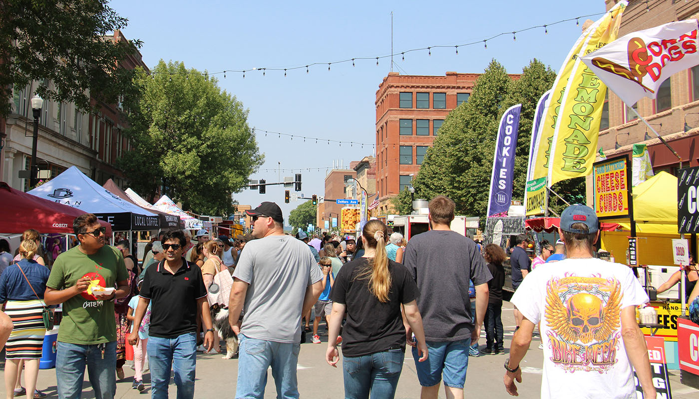 Revelers enjoy the booths and vendors at the Downtown Street Fair in Grand Forks.