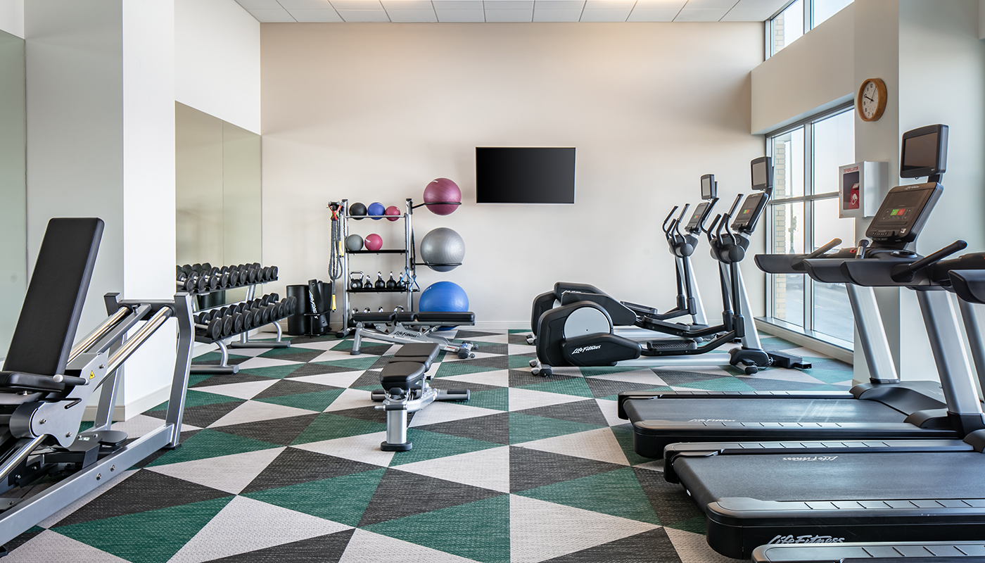 A hotel gym equipped with treadmills, dumbbells and exercise balls.