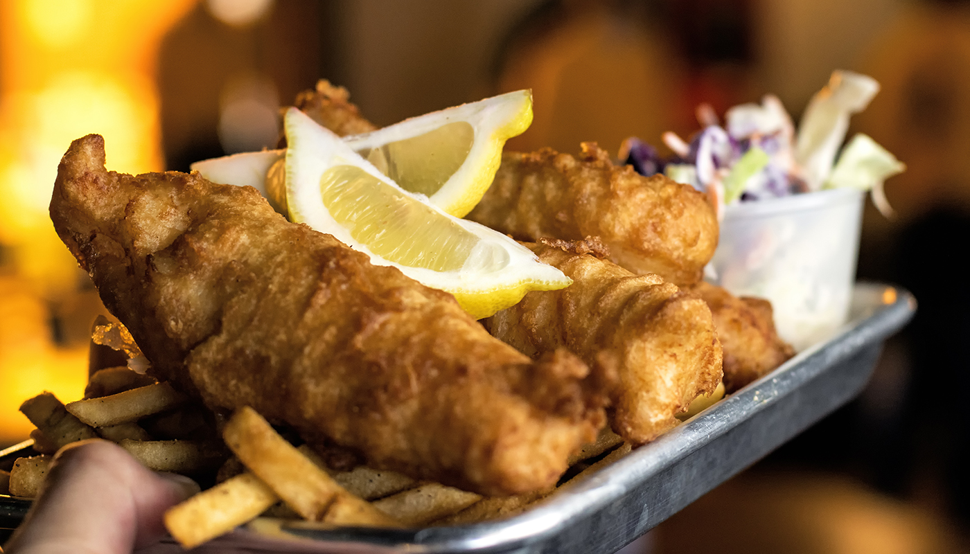 A plate of fish and chips with coleslaw and fries