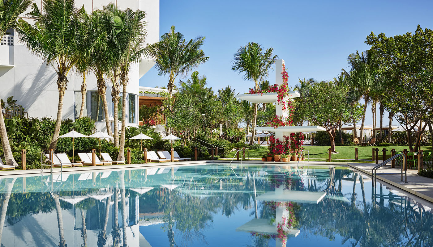 Poolside view of The Miami Beach EDITION hotel with various trees and lounge chairs
