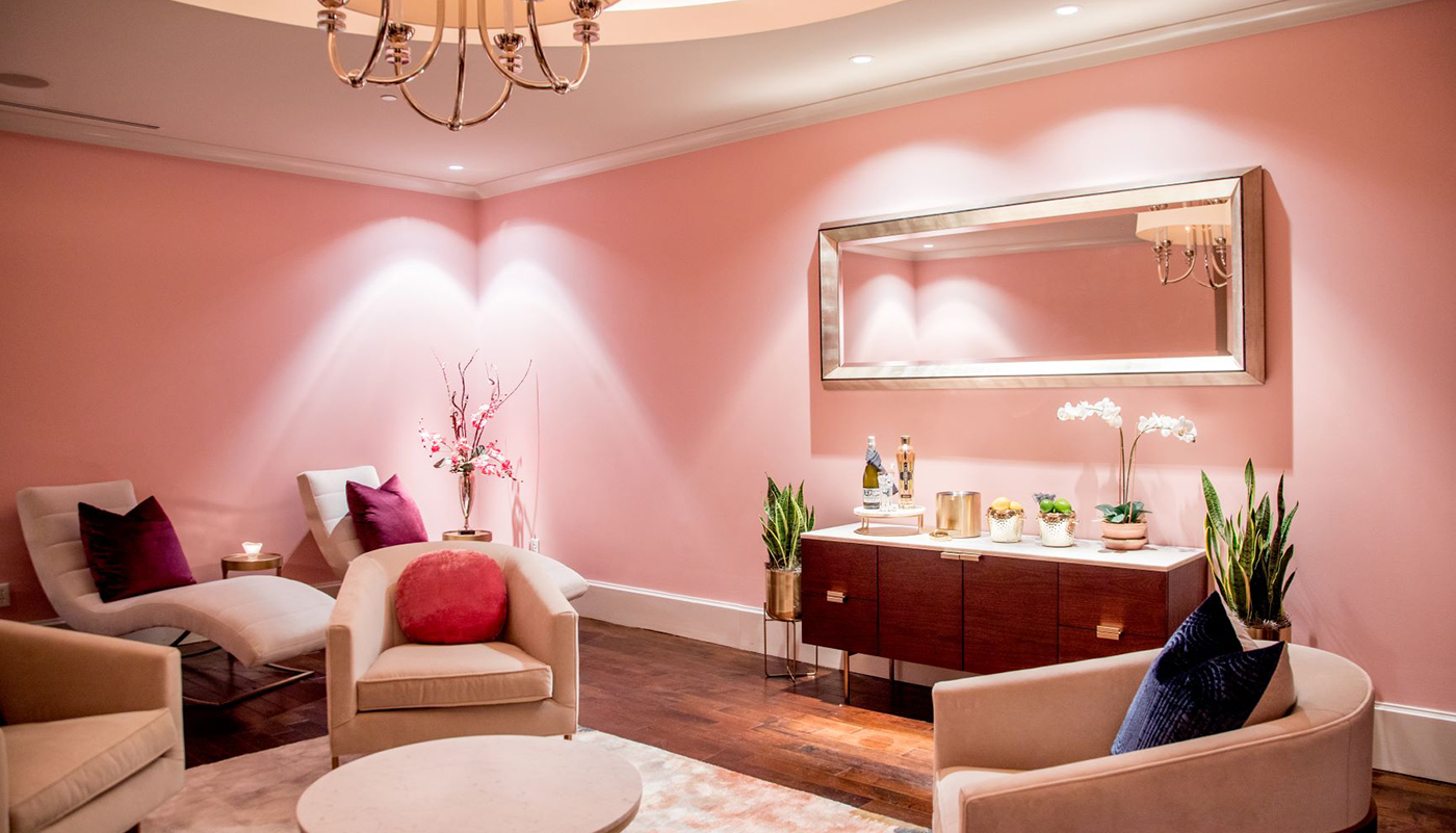 Pink spa treatment room with upholstered chairs and a credenza at The Spa at St. Regis Atlanta