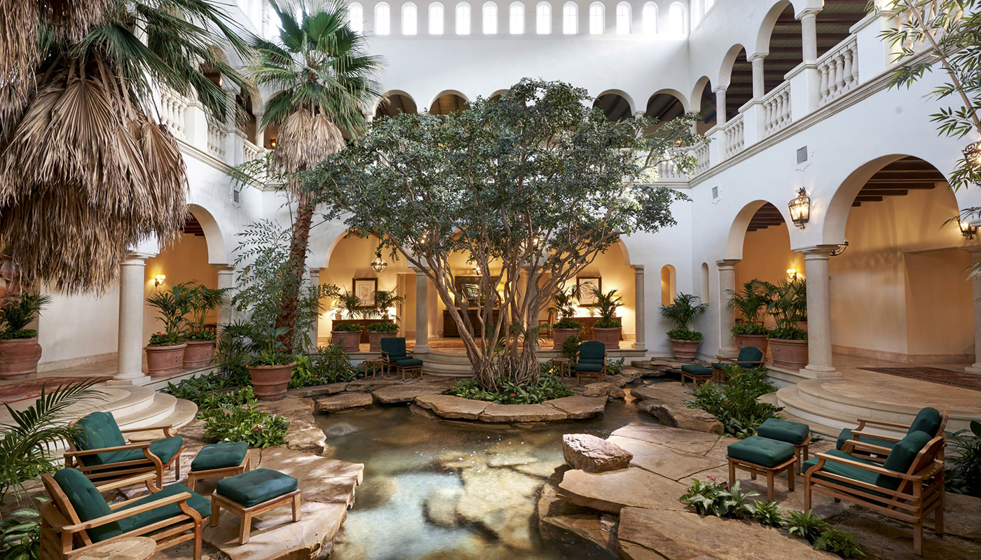Indoor relaxation atrium with sitting areas, trees and plants and small pool of water