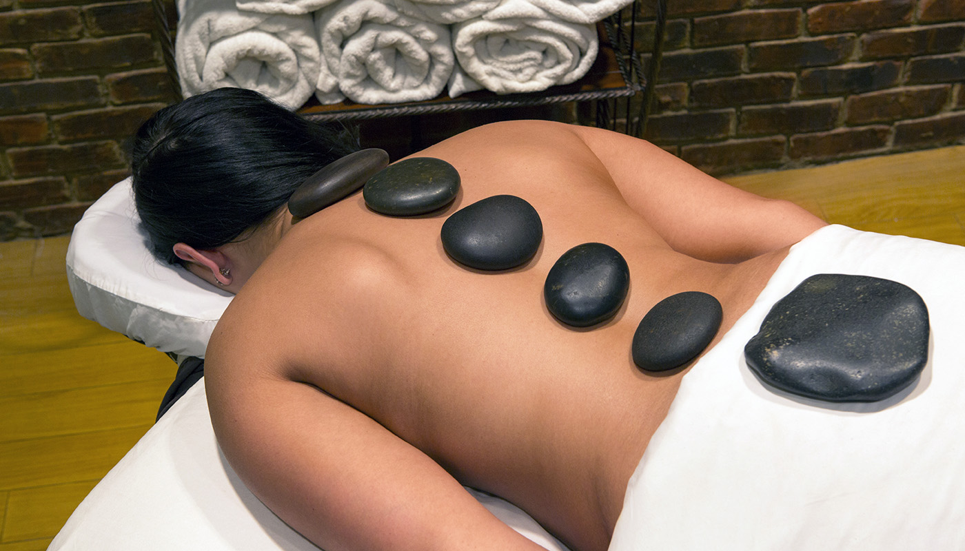 A person receiving a hot stone massage on their back.