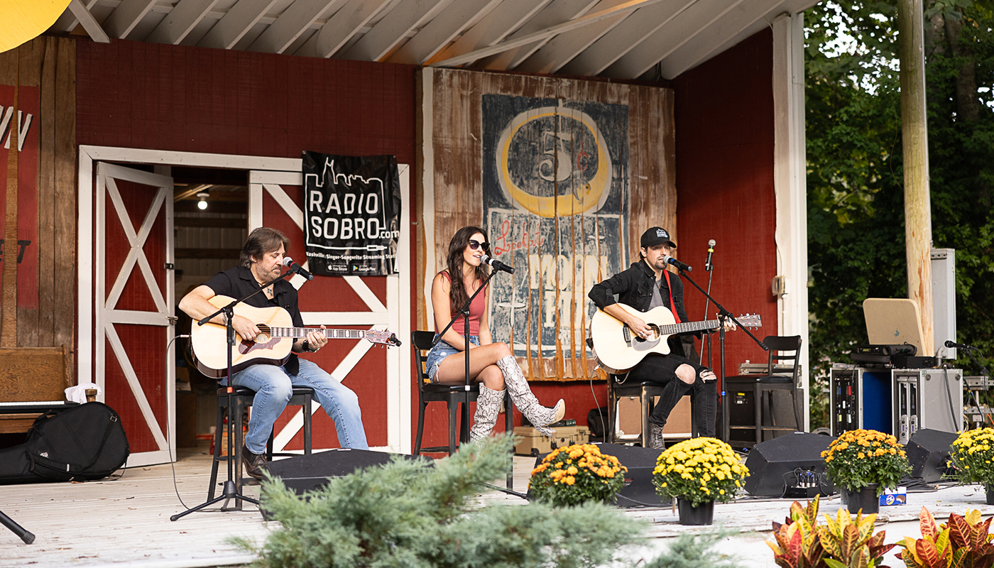 Three musicians perform in an open-air venue during the Bell Buckle Songwriters Festival.
