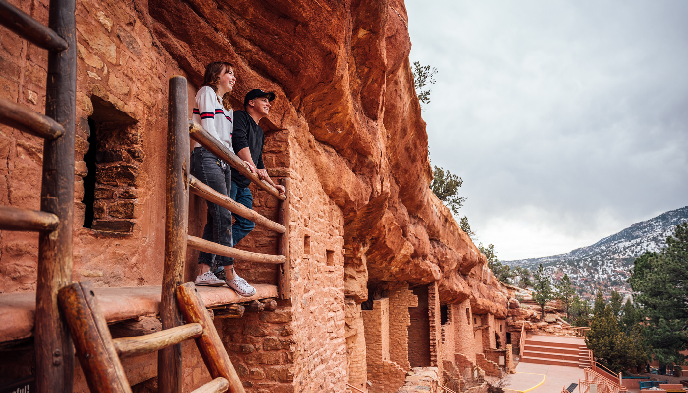A couple looks out from a balcony among the Puebloan cliff dwellings.