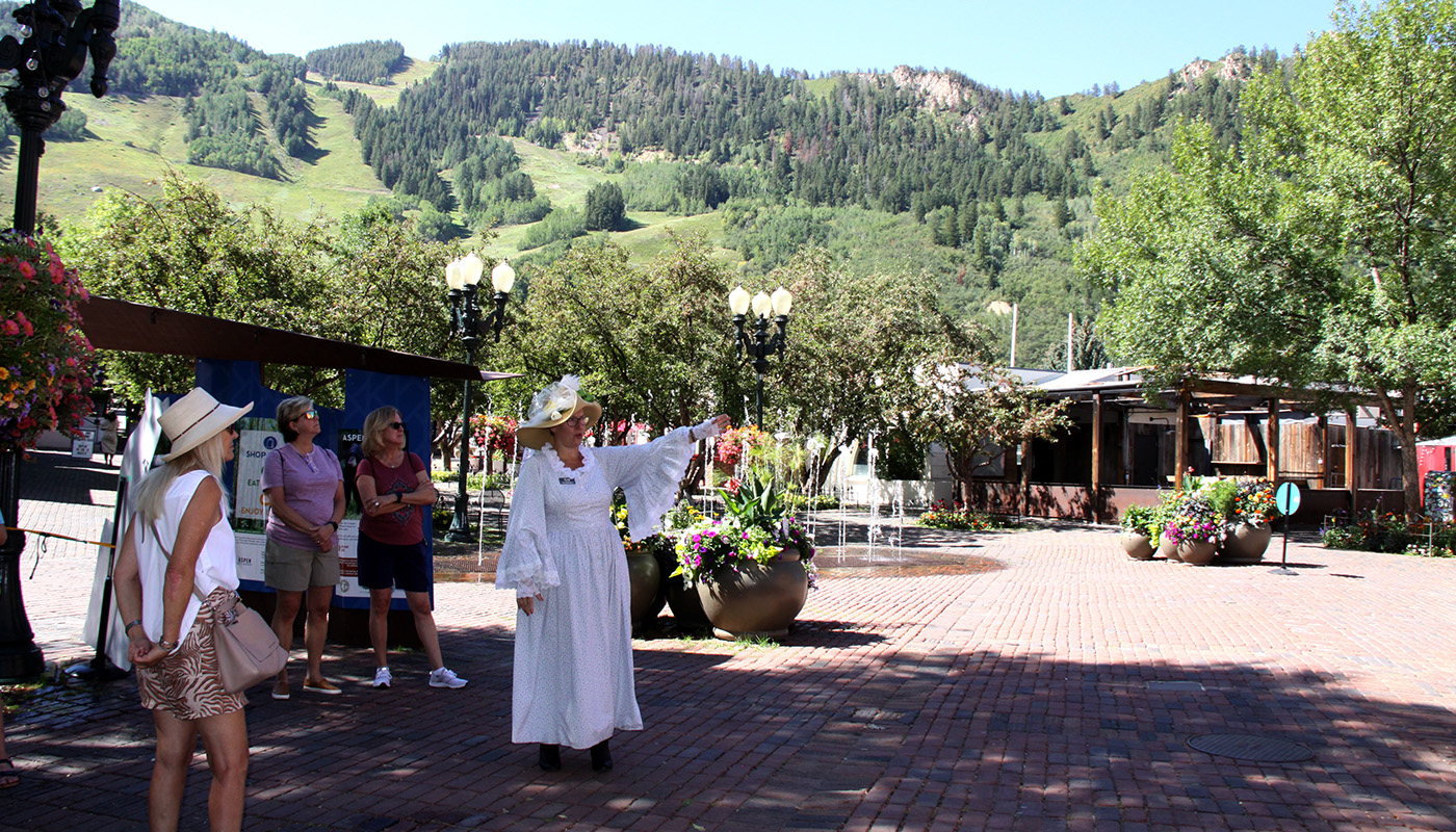 Woman in costume giving a walking tour of downtown Aspen on a bright day