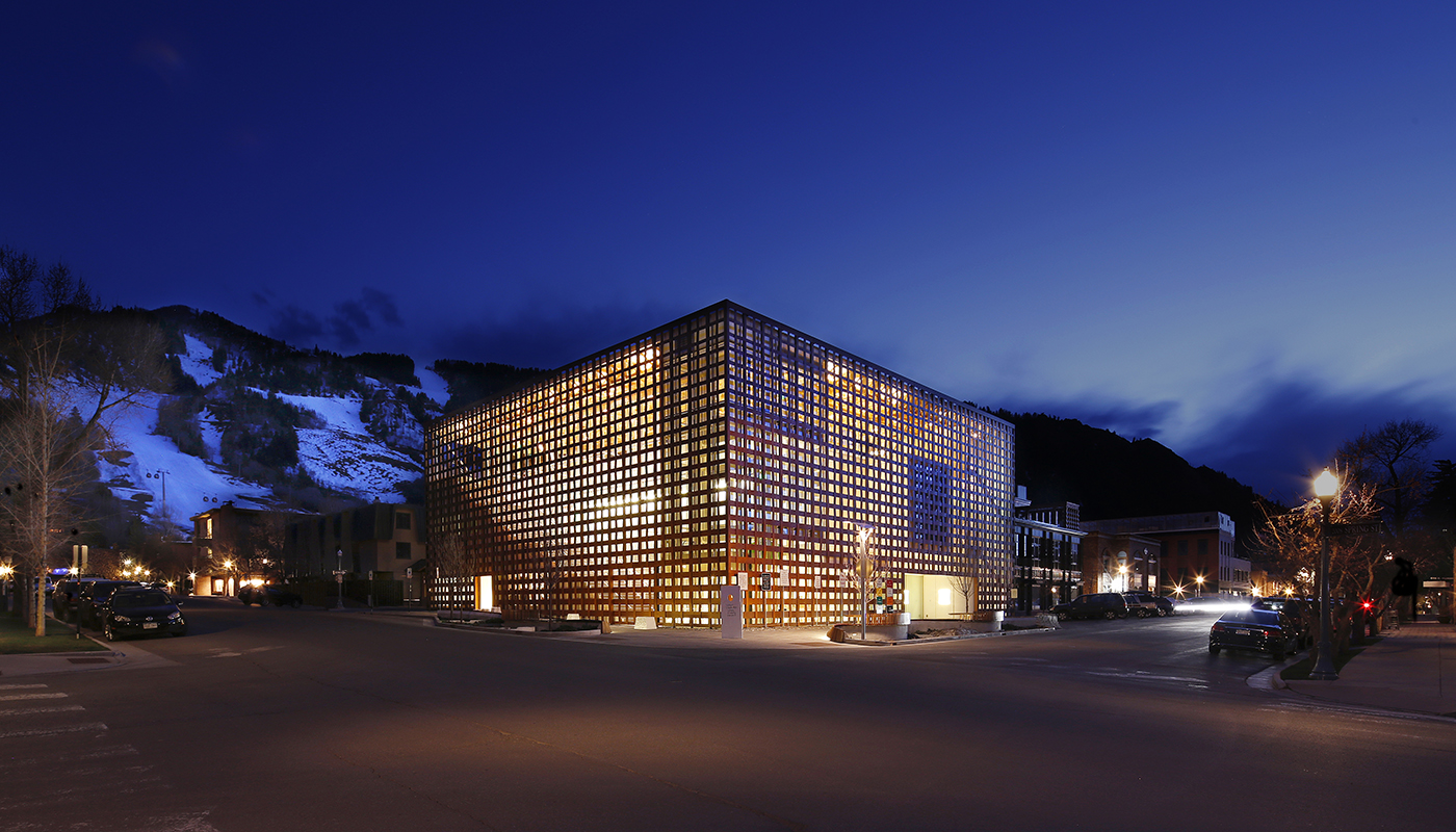 Exterior view of the Aspen Art Museum illuminated at dusk on an empty road