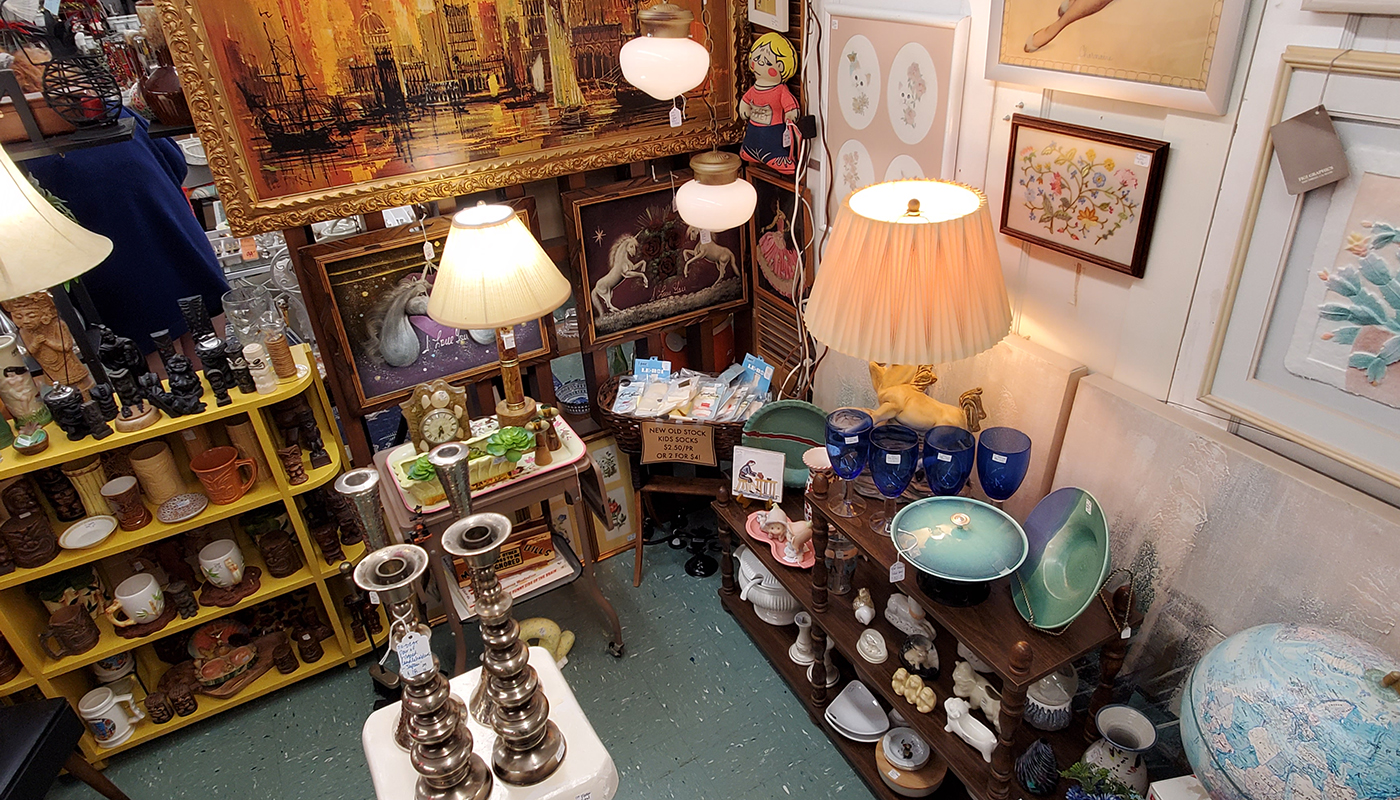 Overhead view of a corner of an antique shop filled with china, lamps and paintings of unicorns. 