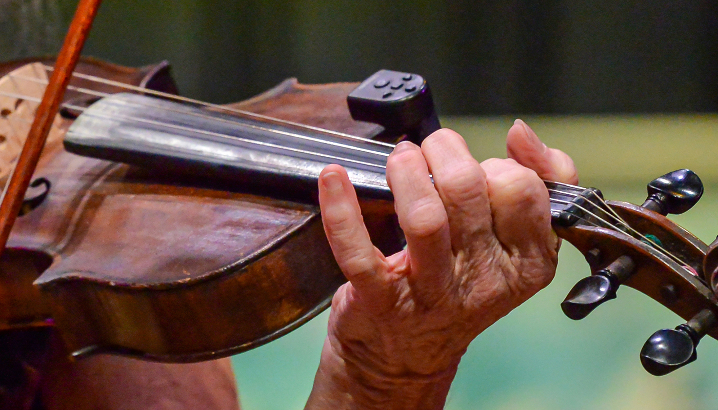 A closeup of a musician playing a fiddle.
