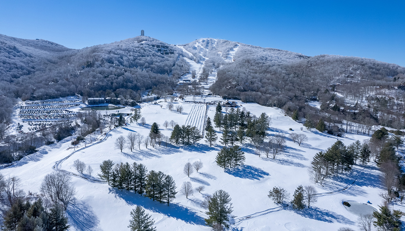 Aerial view of the snowy Sugar Mountain Ski Resort with various trails and trees