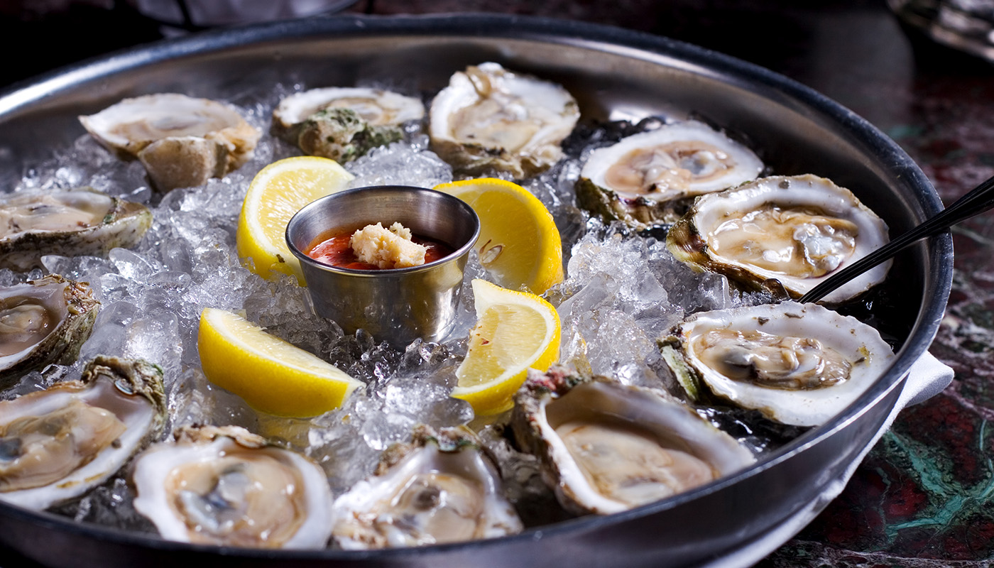 Oysters on the half shell, set in an ice-filled bowl with lemon wedges and cocktail sauce