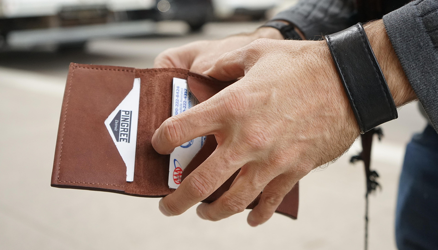 close up shot of a hand opening a leather wallet from Pingree Detroit with a visible AAA Membership card