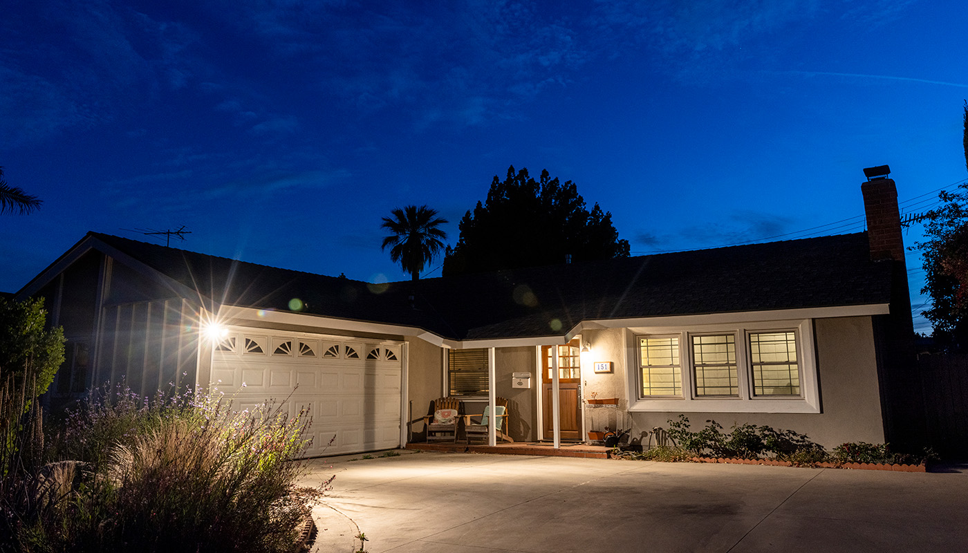 Exterior of home at twilight with lights illuminating driveway