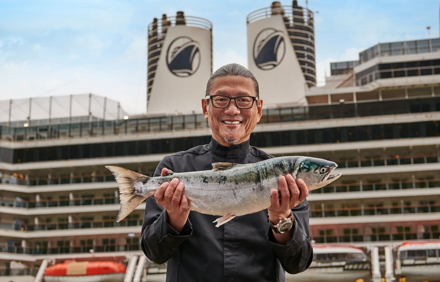 Holland America chef on board a ship holding a fish.