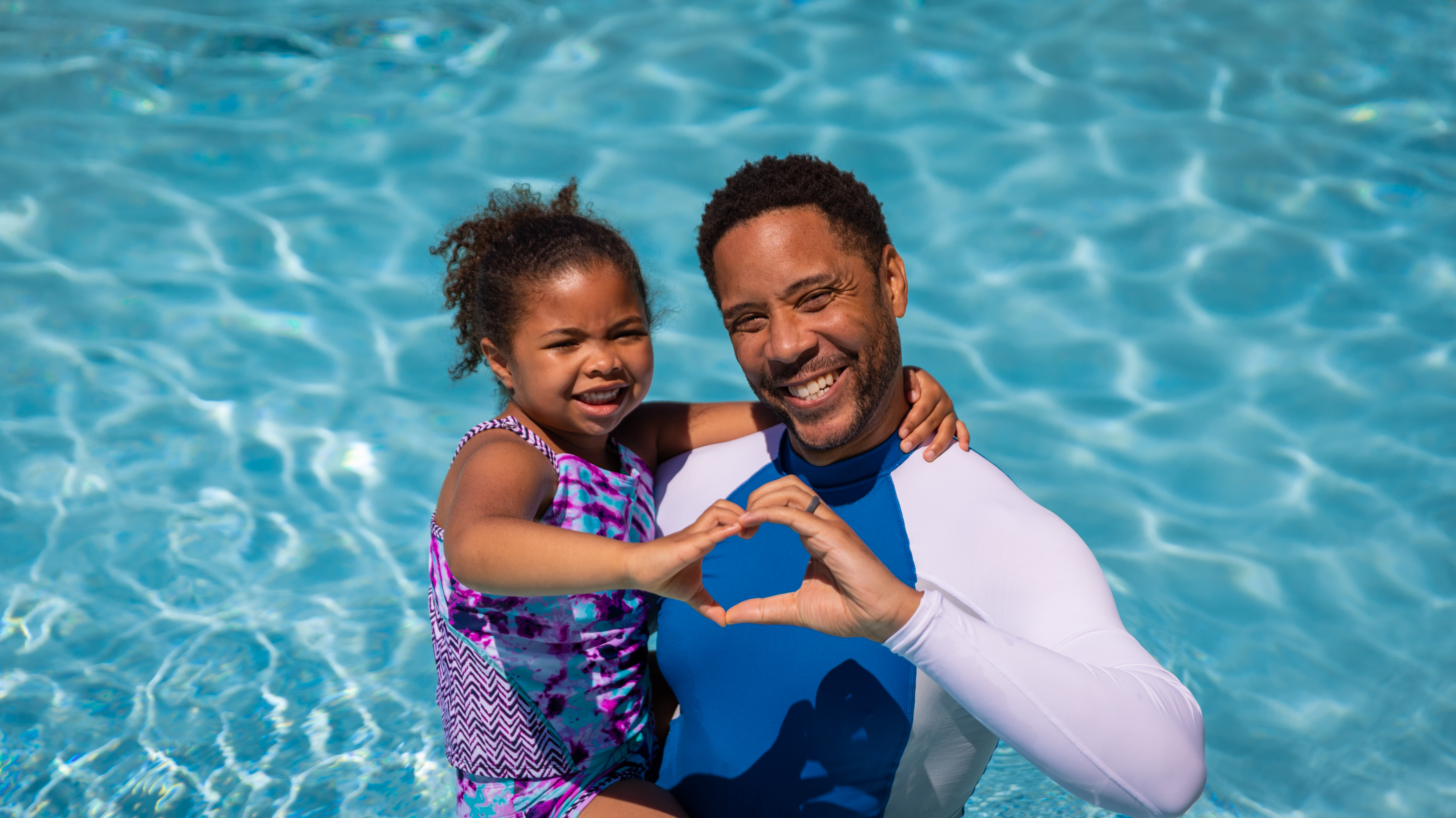 Young father with his daughter making a heart shape with their hands.