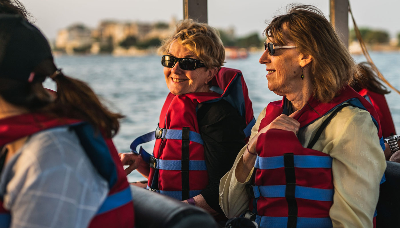 Two woman with life vests on an open-air tour boat.