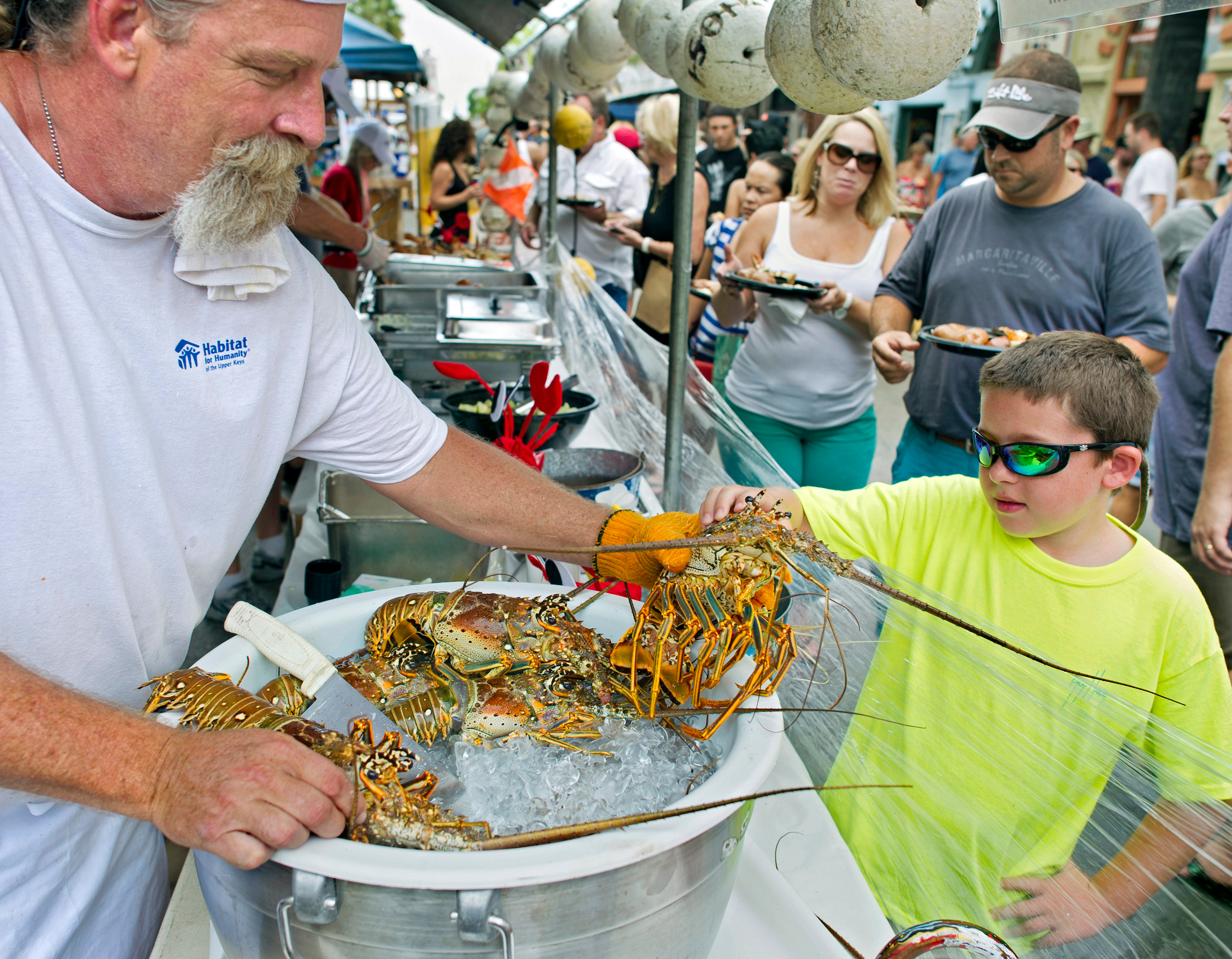 A lobster fest in Florida with an older man surving food to a young boy.