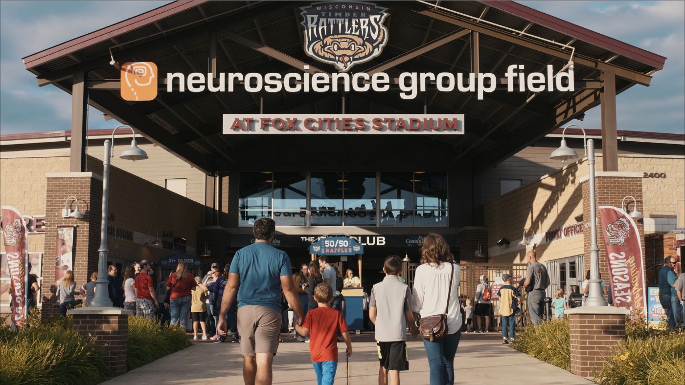 Family approaching the entrance gates of Fox Cities Stadium for a Timber Rattler baseball game.