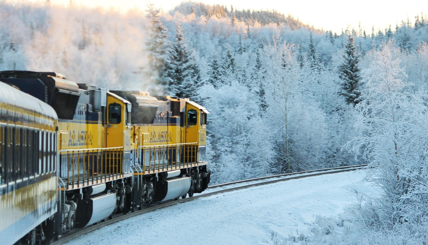 A train traveling through a frozen winter scene in Alaska