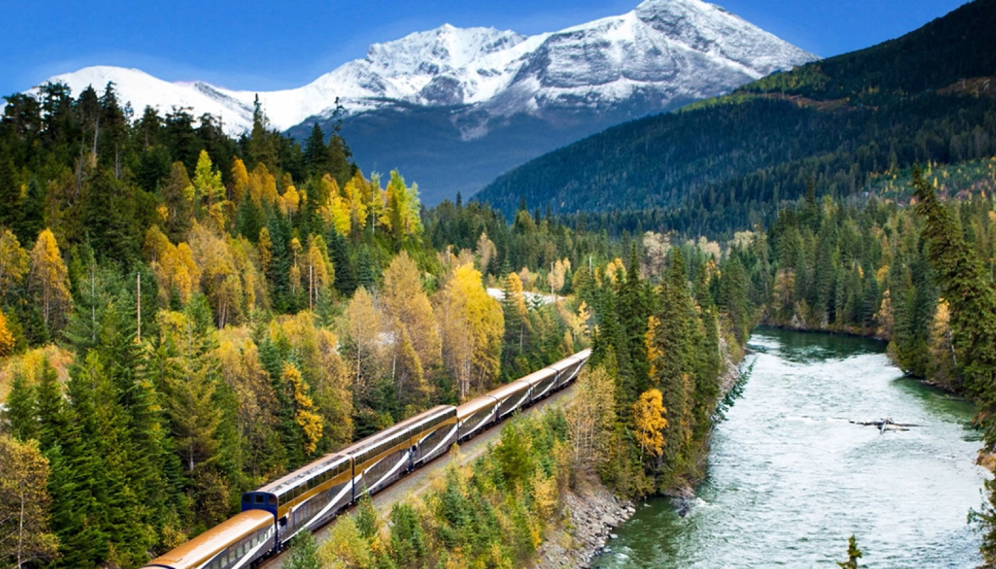 Train passing along a valley rail line along a river bank